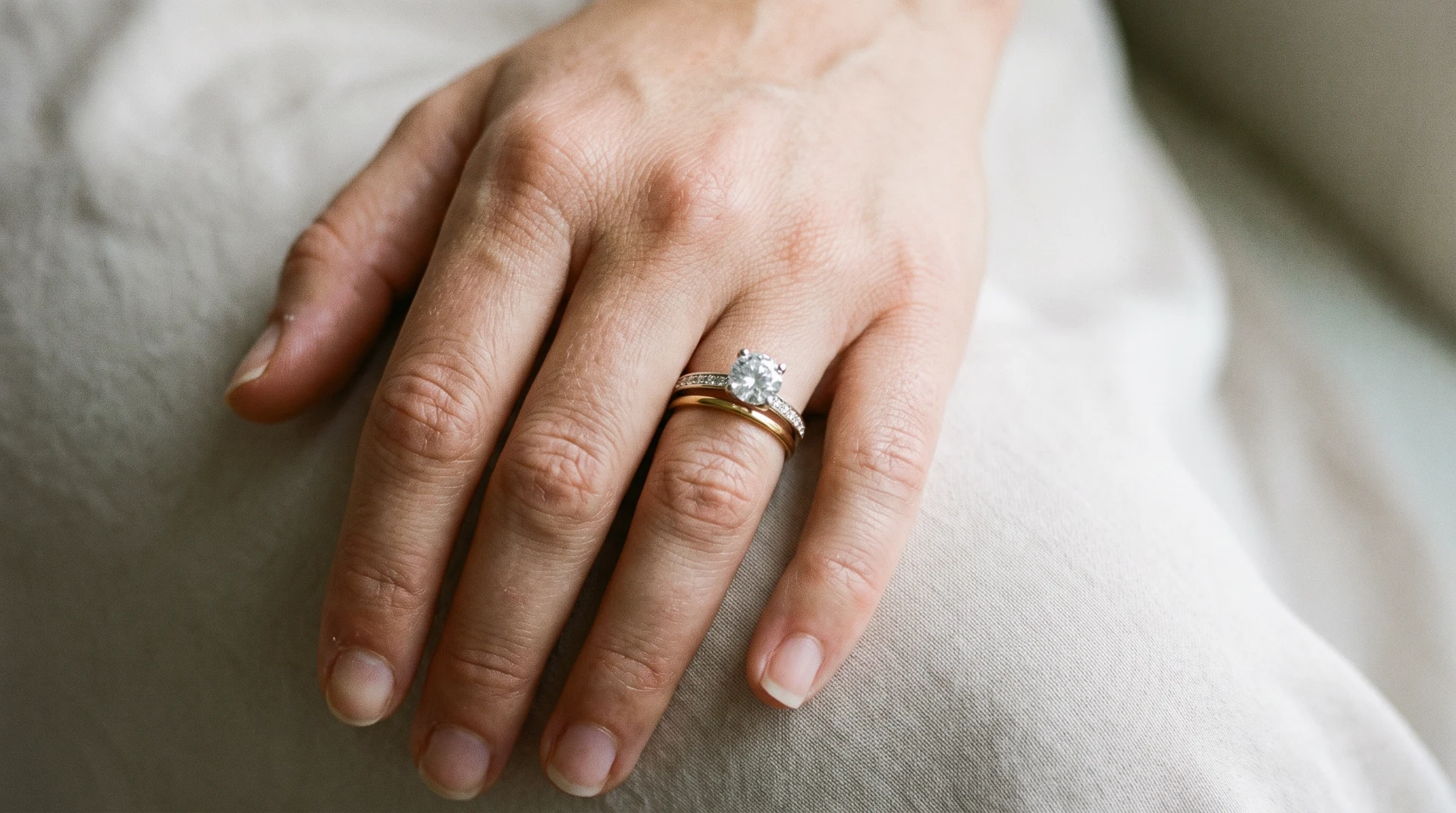 Anel solitário de noivado e aliança de casamento usados juntos no mesmo dedo
